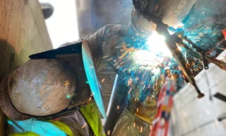 worker with a helmet welding some metal structures